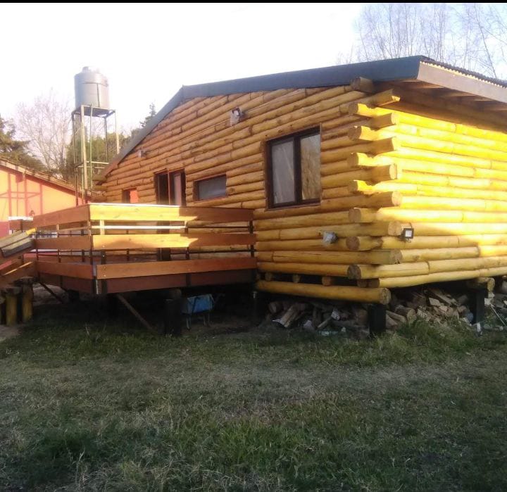 Cabaña de tronco con deck de madera y escalera