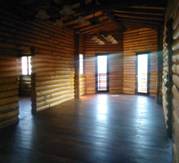 Interior amplio de cabaña con techo a dos aguas y pisos de madera brillante